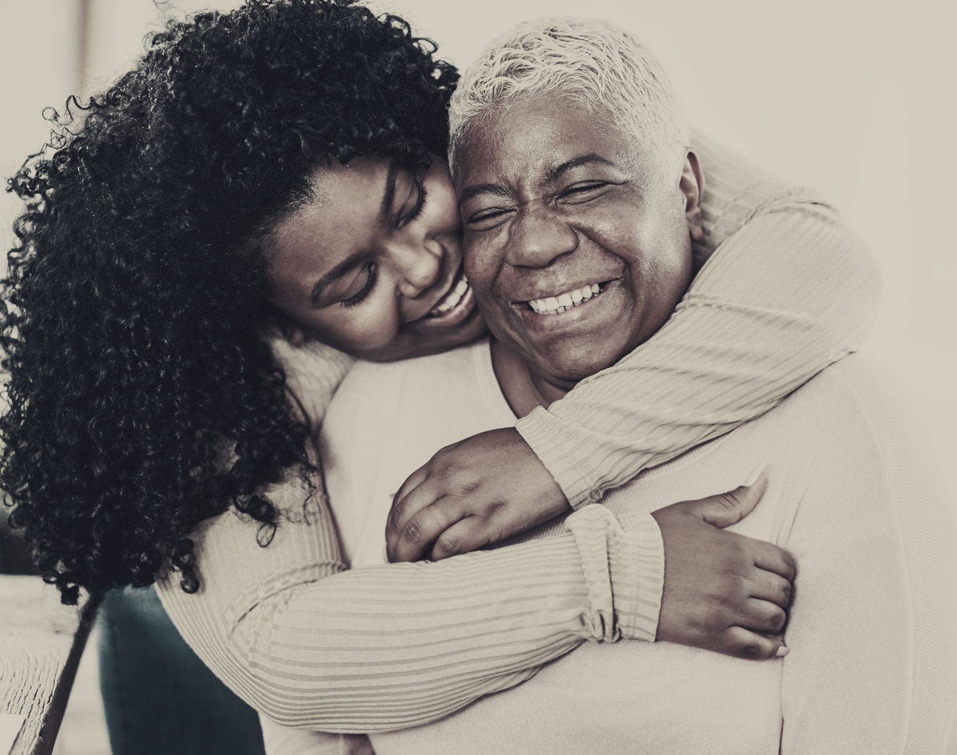 A young woman is hugging an older woman in a living room.