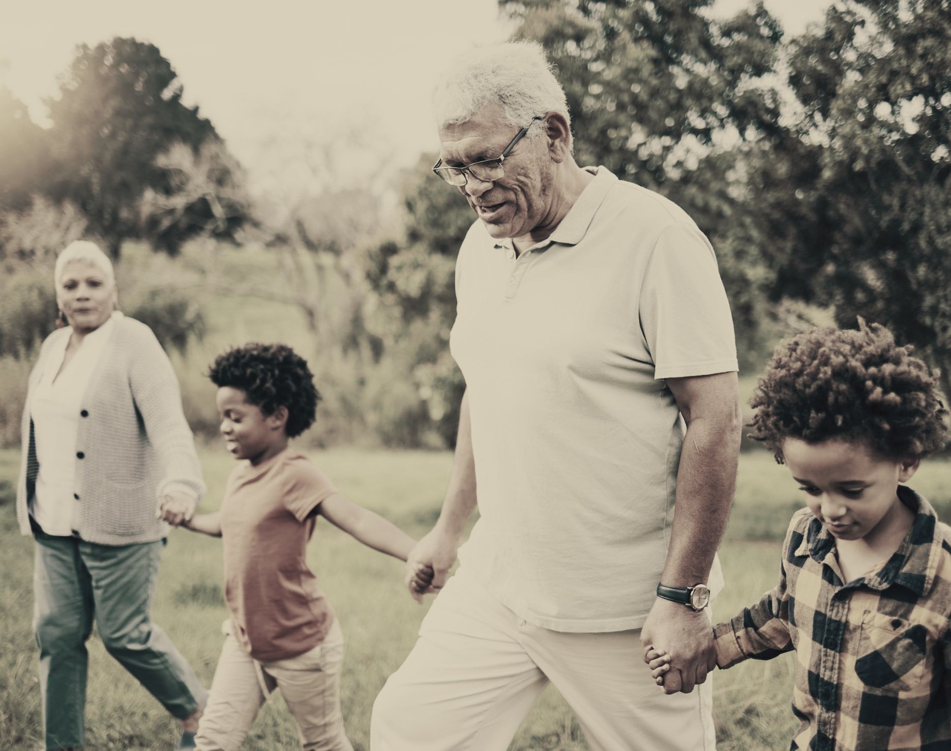 A family is walking through a park holding hands.