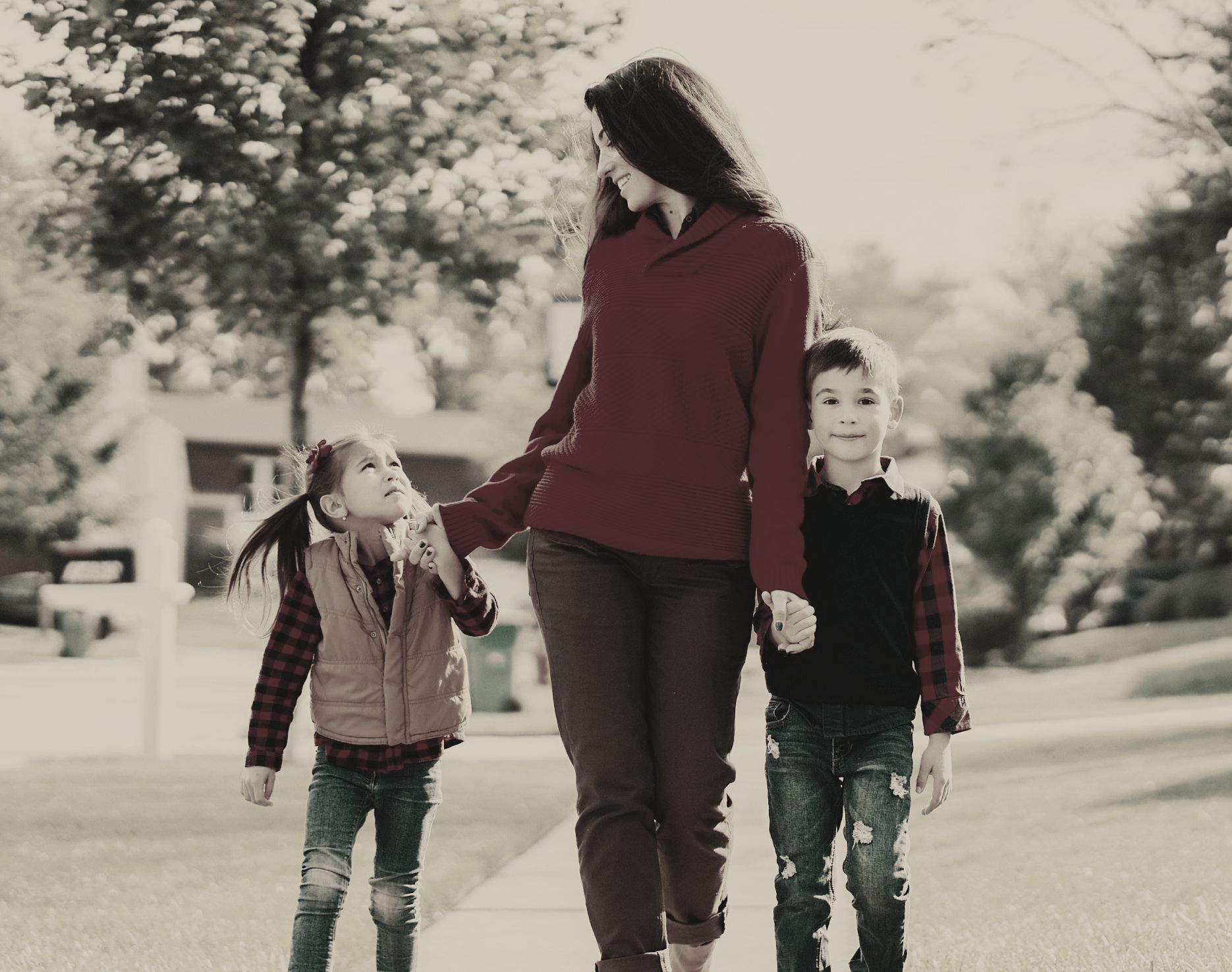 A woman and two children are walking down a sidewalk holding hands