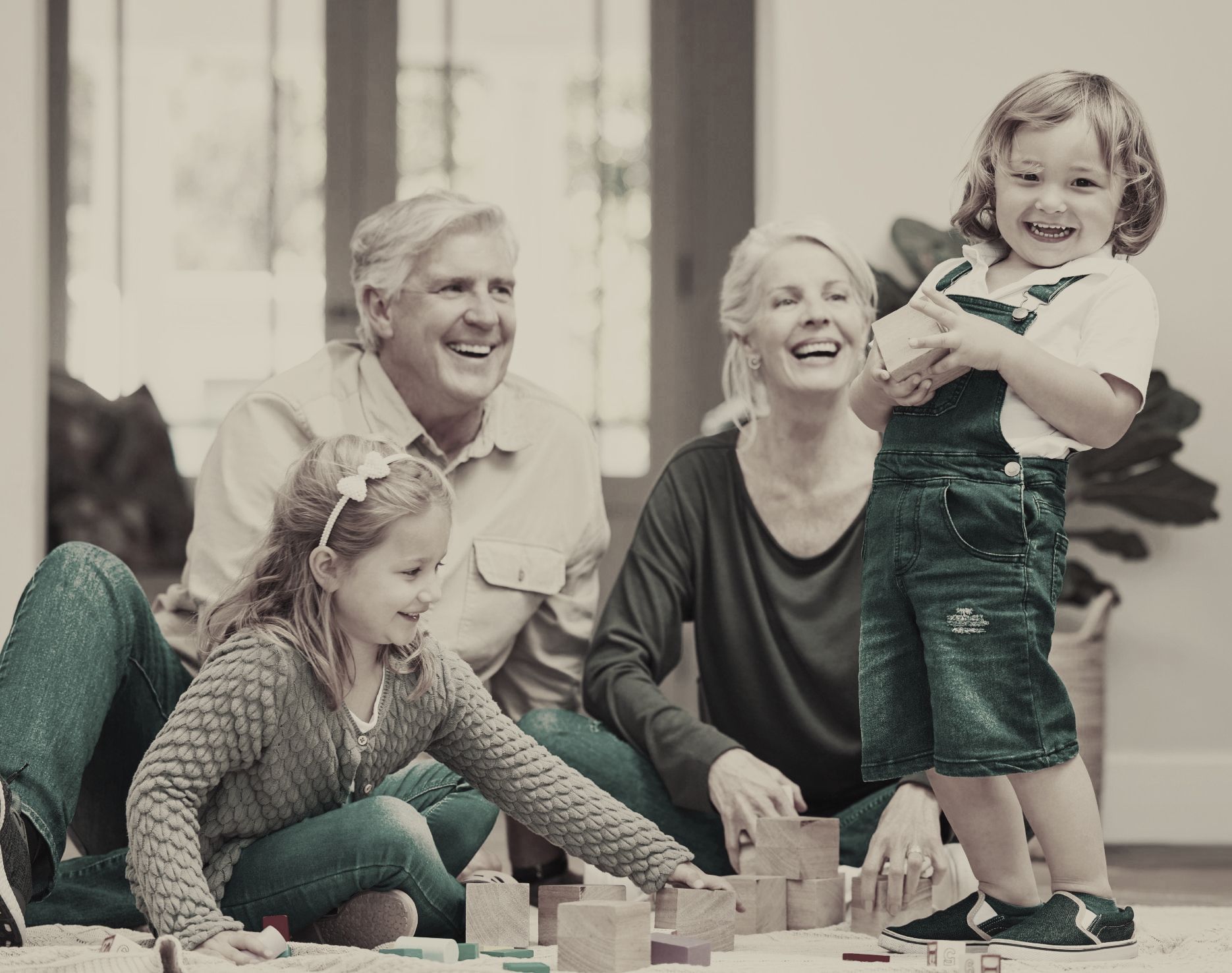 A family is sitting on the floor playing with wooden blocks.