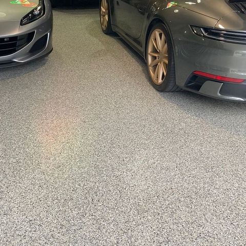 Two cars are parked in a garage with a gray floor.