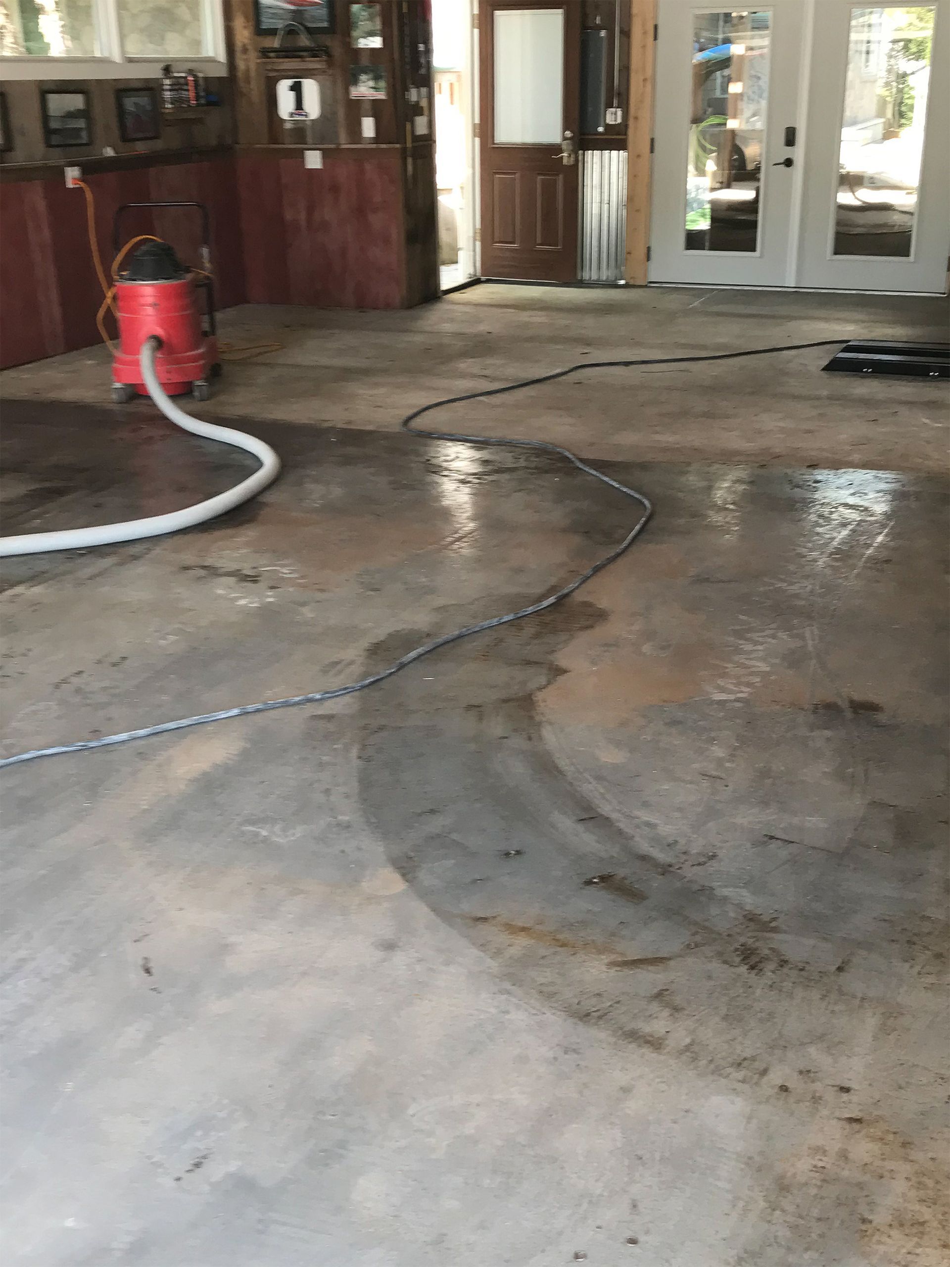 A red vacuum cleaner is sitting on a dirty concrete floor