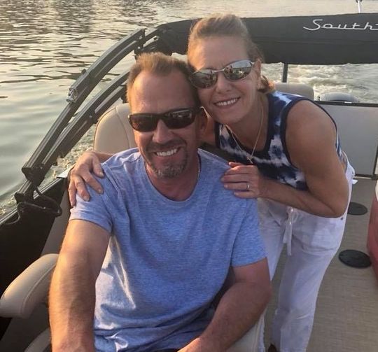 A man and woman are posing for a picture on a pontoon boat