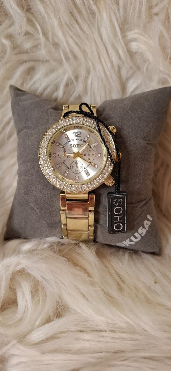 Un reloj de oro está encima de una almohada.