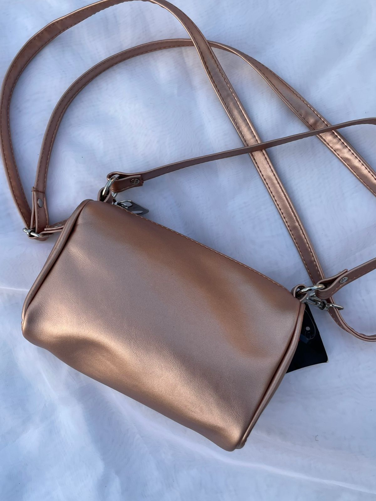 Un pequeño bolso metálico con una correa larga.