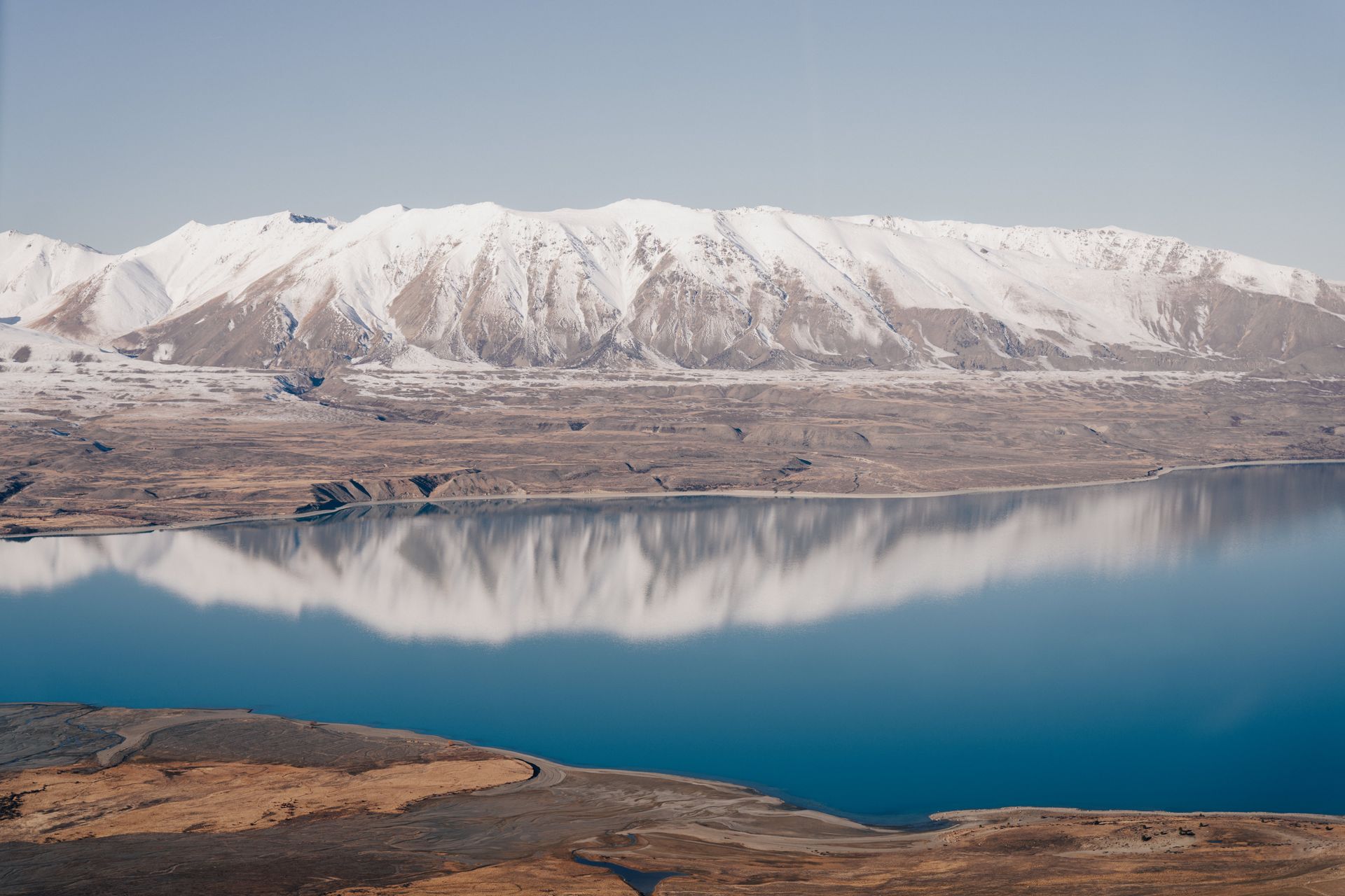 A lake with mountains in the background and a reflection of the mountains in the water.