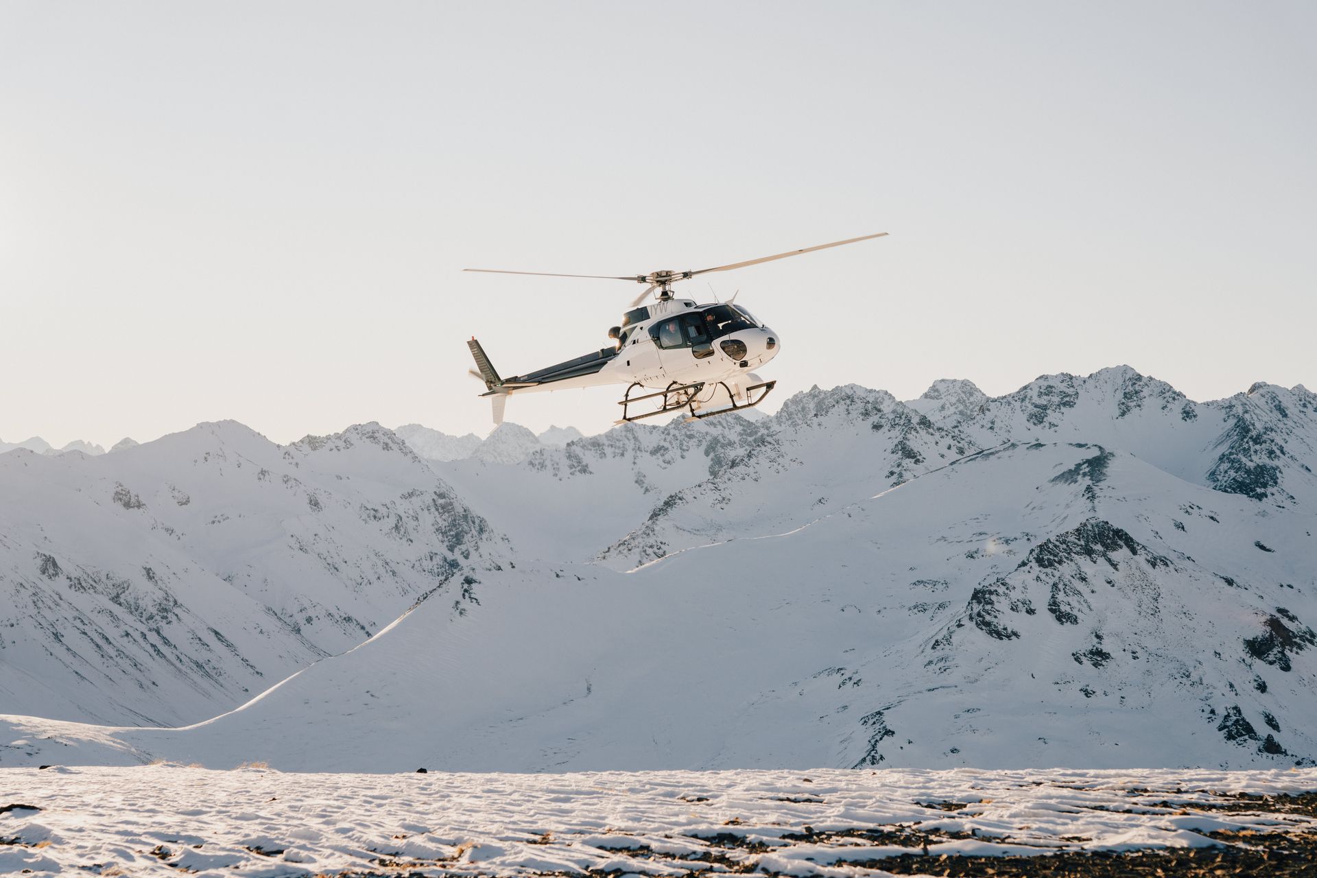 A helicopter is flying over a snowy mountain.