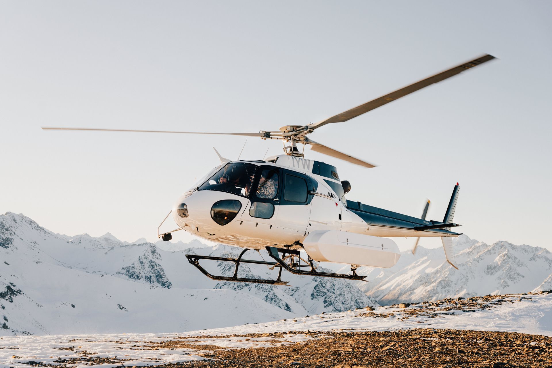 A helicopter is flying over a snowy mountain.