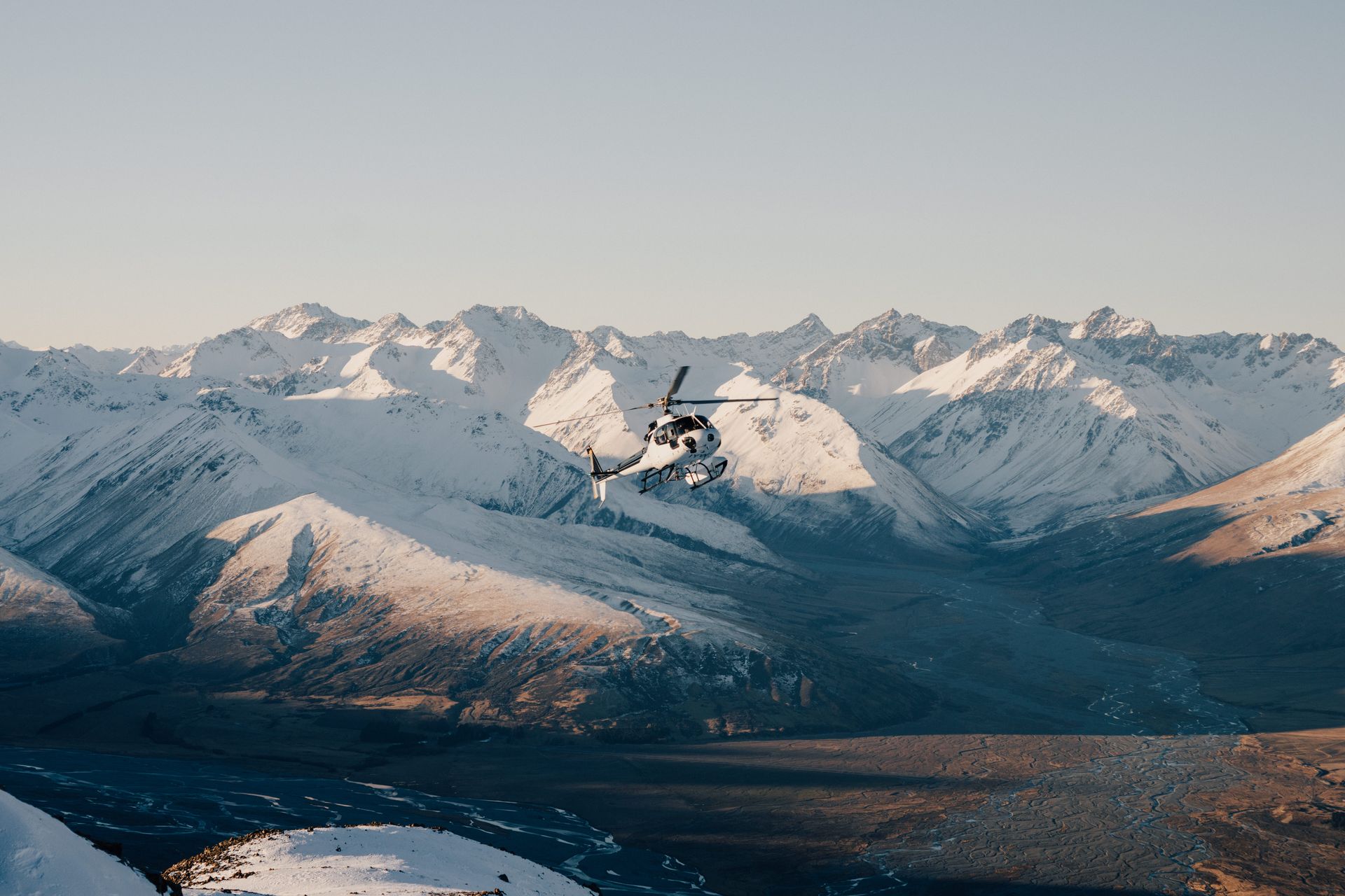 A helicopter is flying over a snowy mountain range.High Country Outfitters