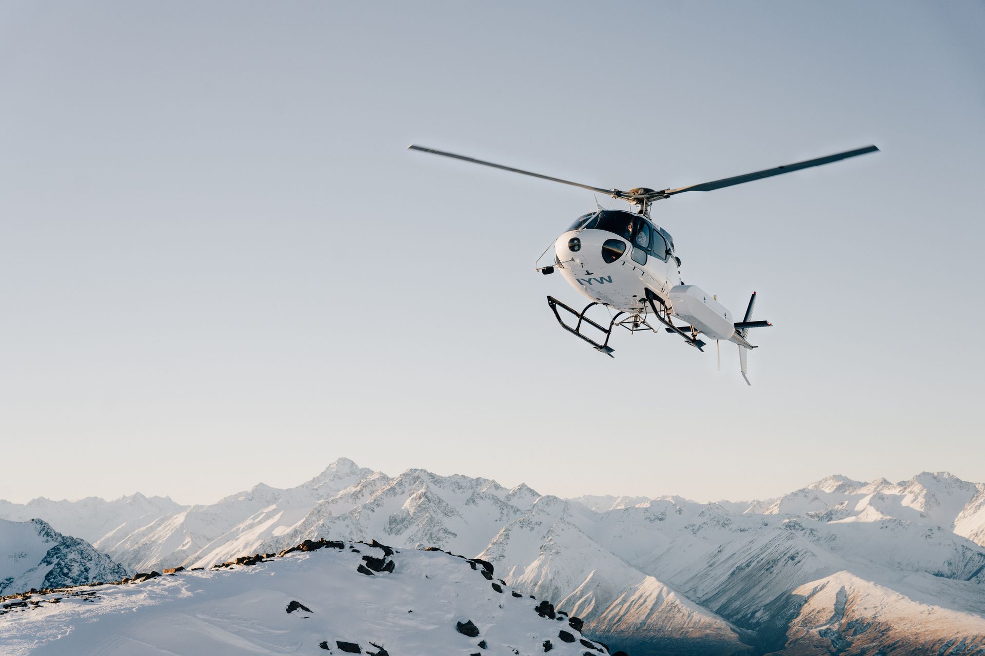 A helicopter is flying over a snowy mountain.High Country Outfitters