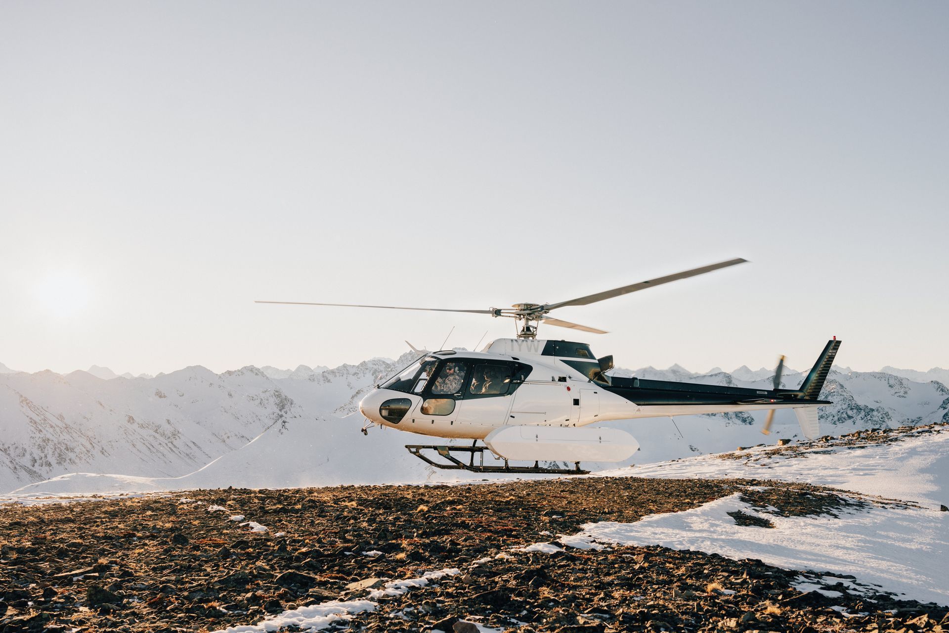 A helicopter is flying over a snowy mountain.