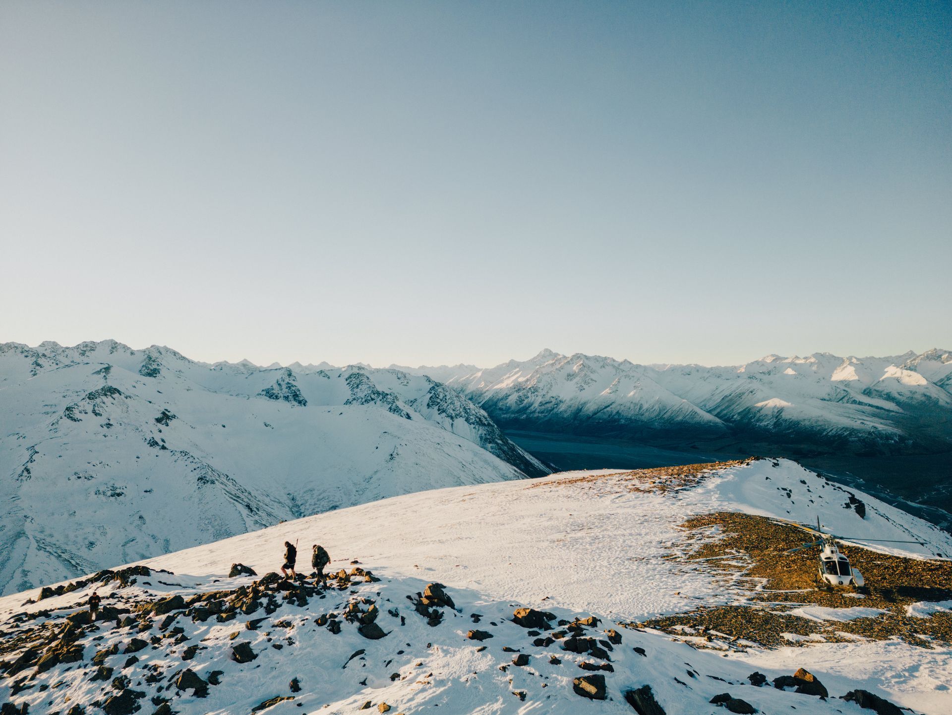 Two people are standing on top of a snow covered mountain.