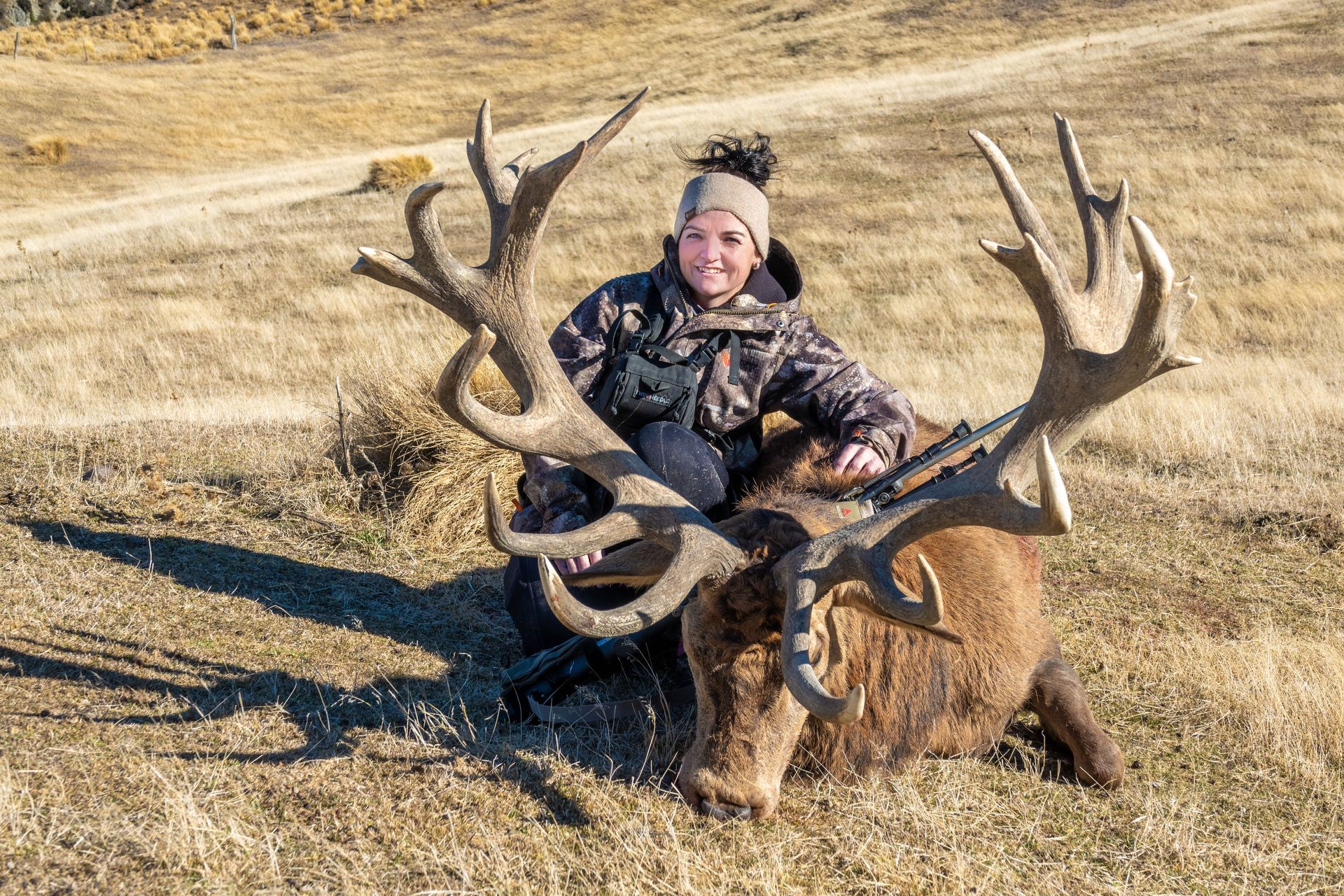 A woman is sitting on top of a large deer in a field.High Country Outfitters