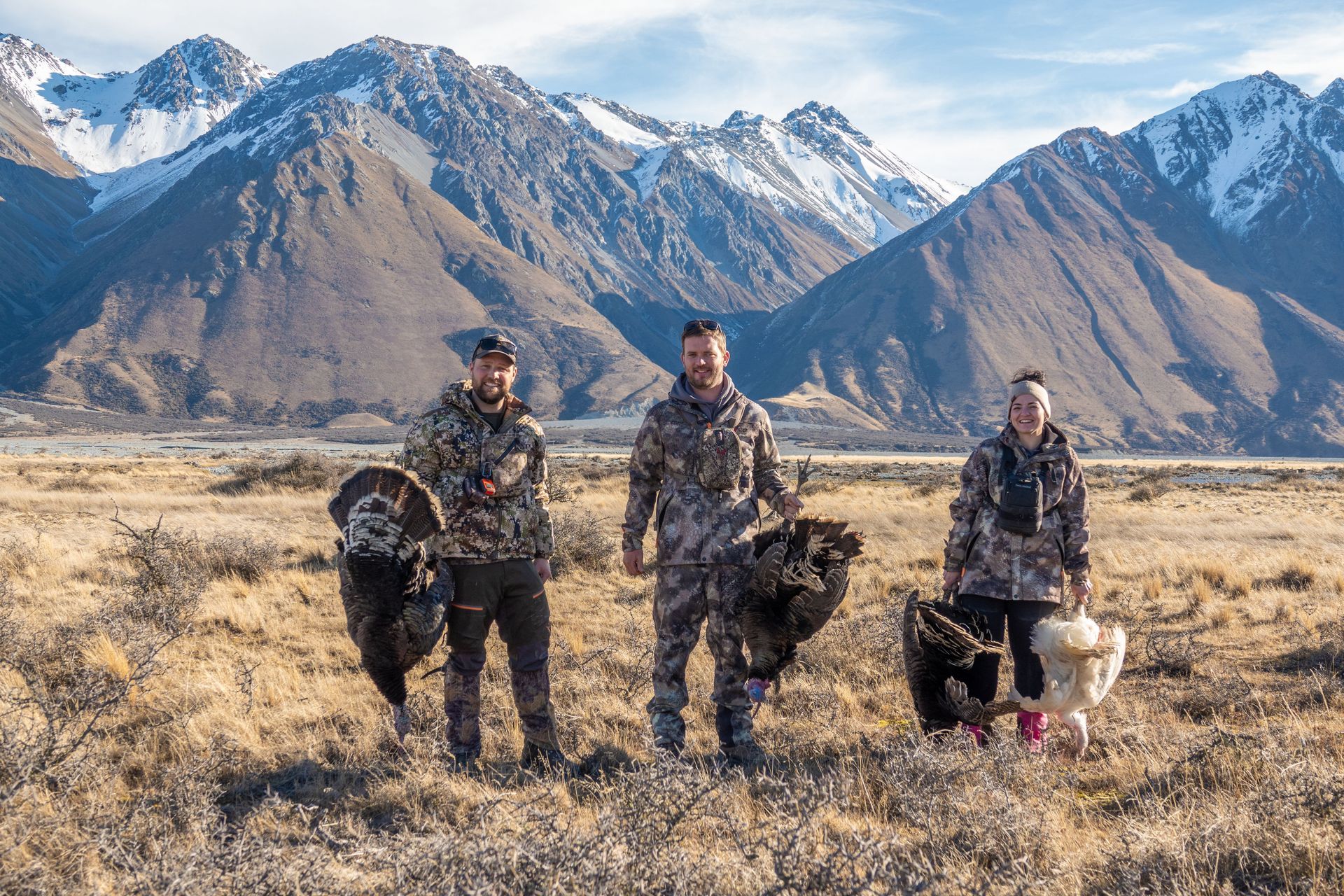 A group of people are standing in a field with mountains in the background.