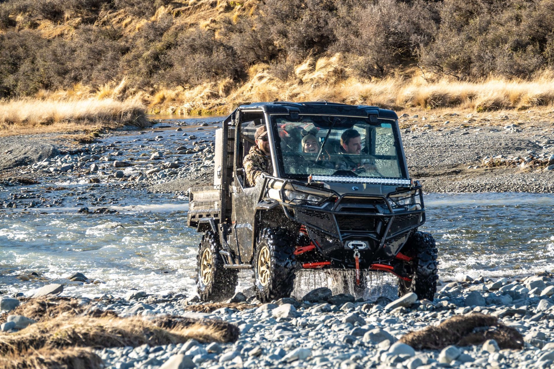 A man is driving a utility vehicle through a river.
