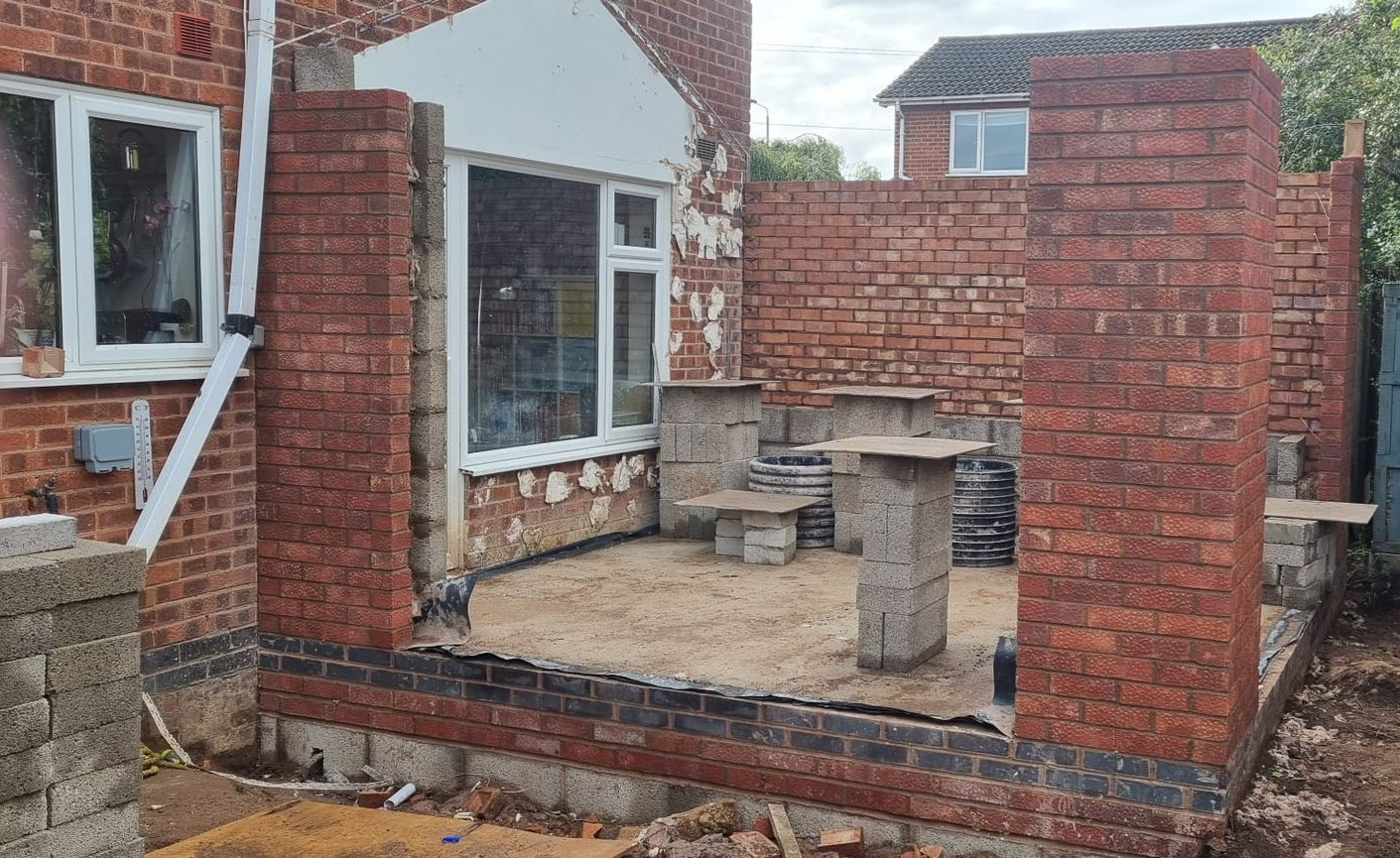 Brick structure under construction, partially demolished, with a window and concrete slabs.