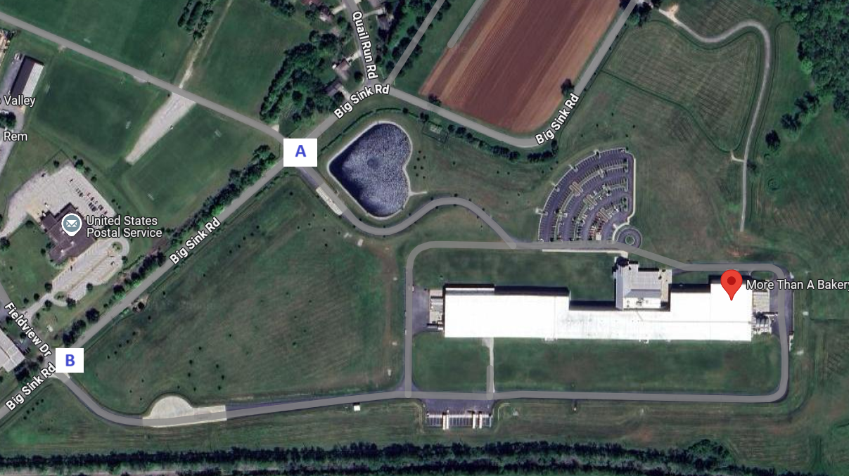 Aerial view:More Than A Bakery campus with parking, fields, and a heart-shaped water feature.