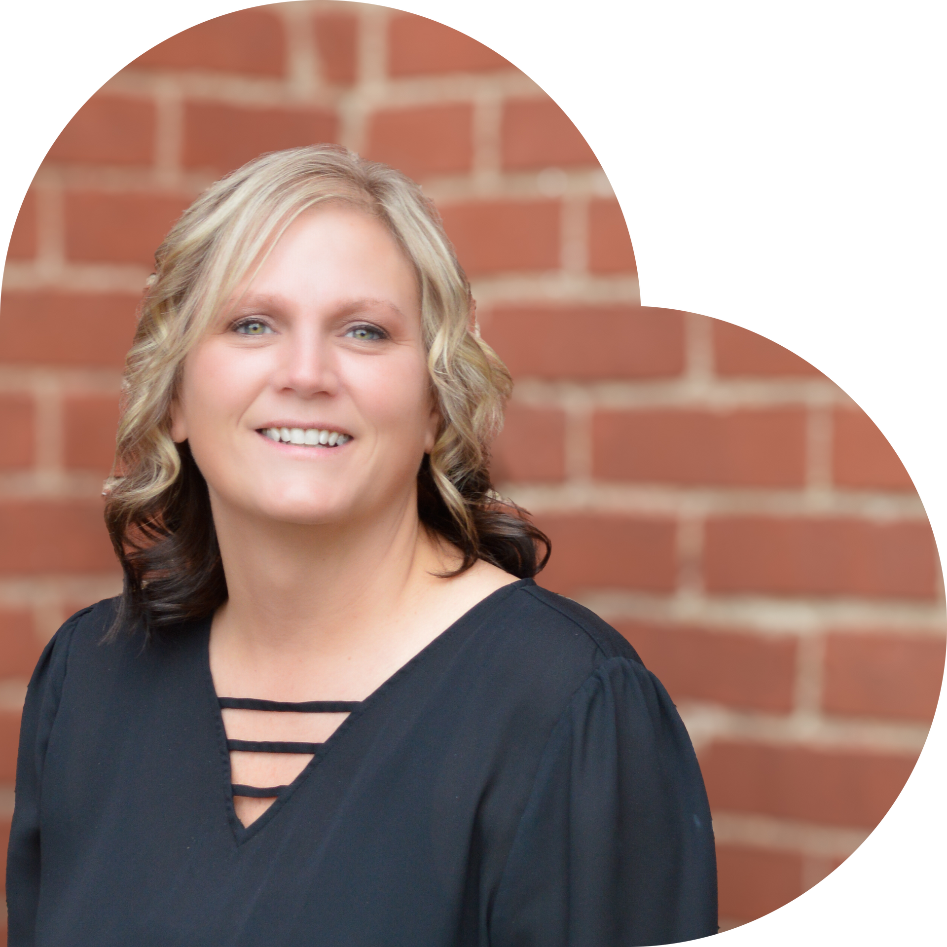 Woman in a black blouse smiles, set against a brick heart-shaped background.