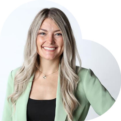 Woman in a green blazer smiles, set against a light grey heart-shaped background.