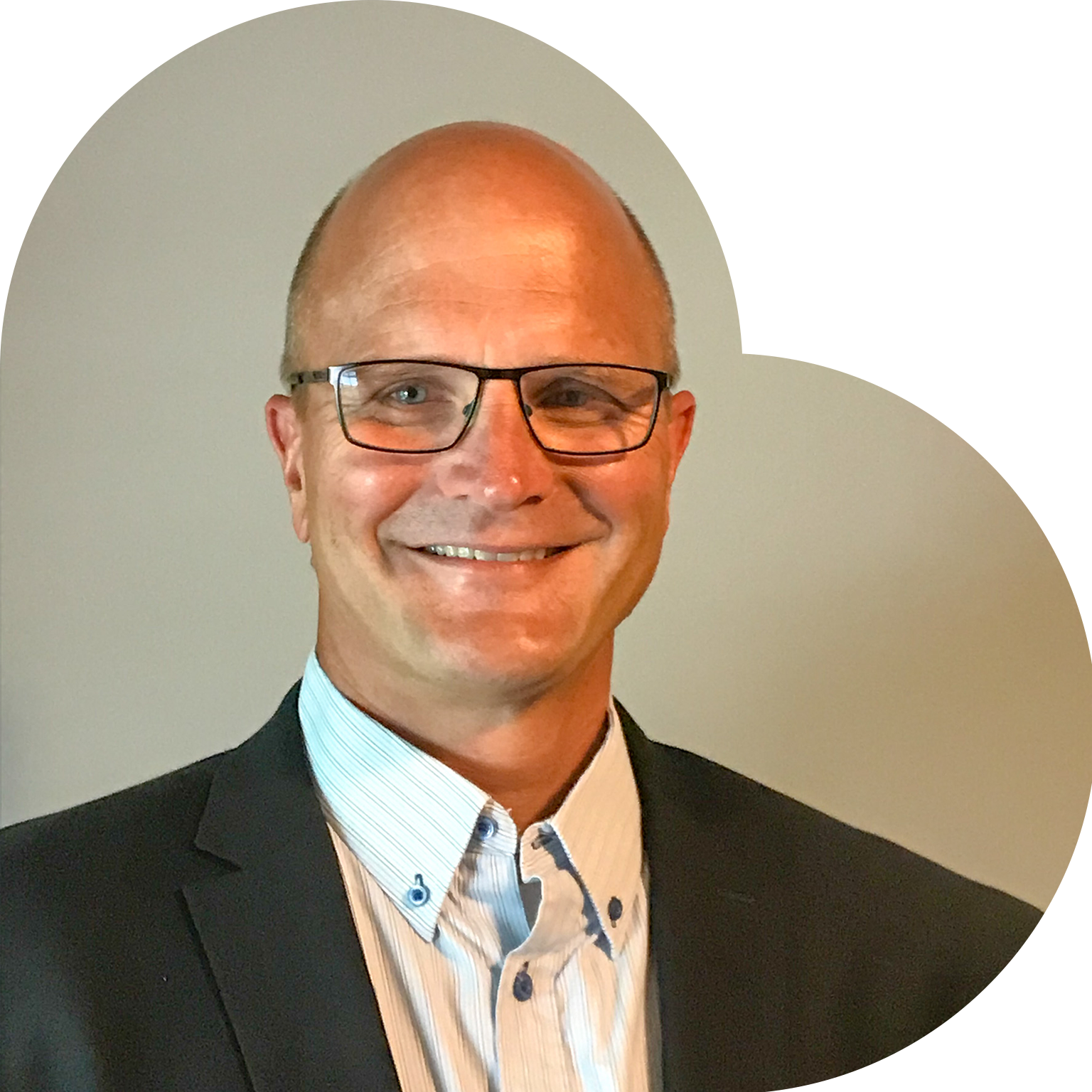 Man in a suit smiling, set against a tan heart-shaped background.
