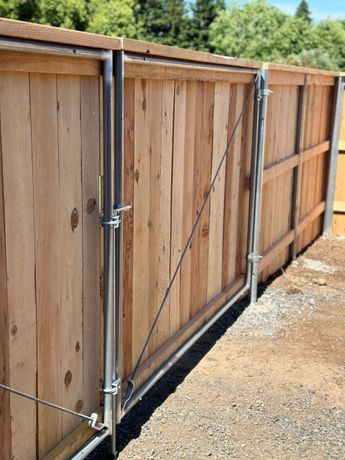 A black fence is surrounding a brick driveway in a residential area.