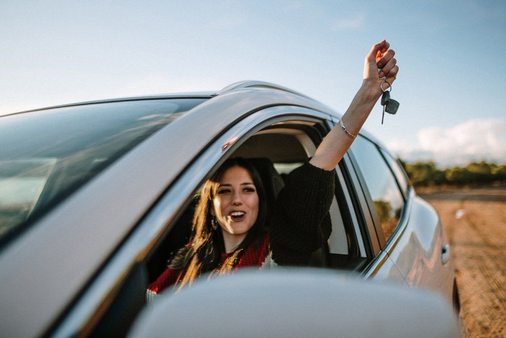 Happy Woman Holding a Key Inside of Her Car — Goddard, KS — Ungles Independent Insurance Group