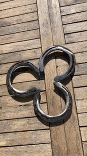 Une paire de fers à cheval posée sur une table en bois.