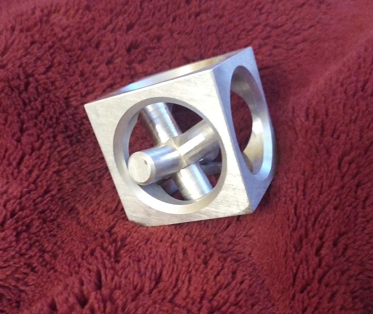 Un cube d'argent avec des trous est posé sur une couverture rouge