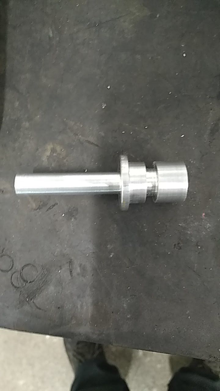 Une personne se tient debout à côté d'un morceau de métal sur une table.