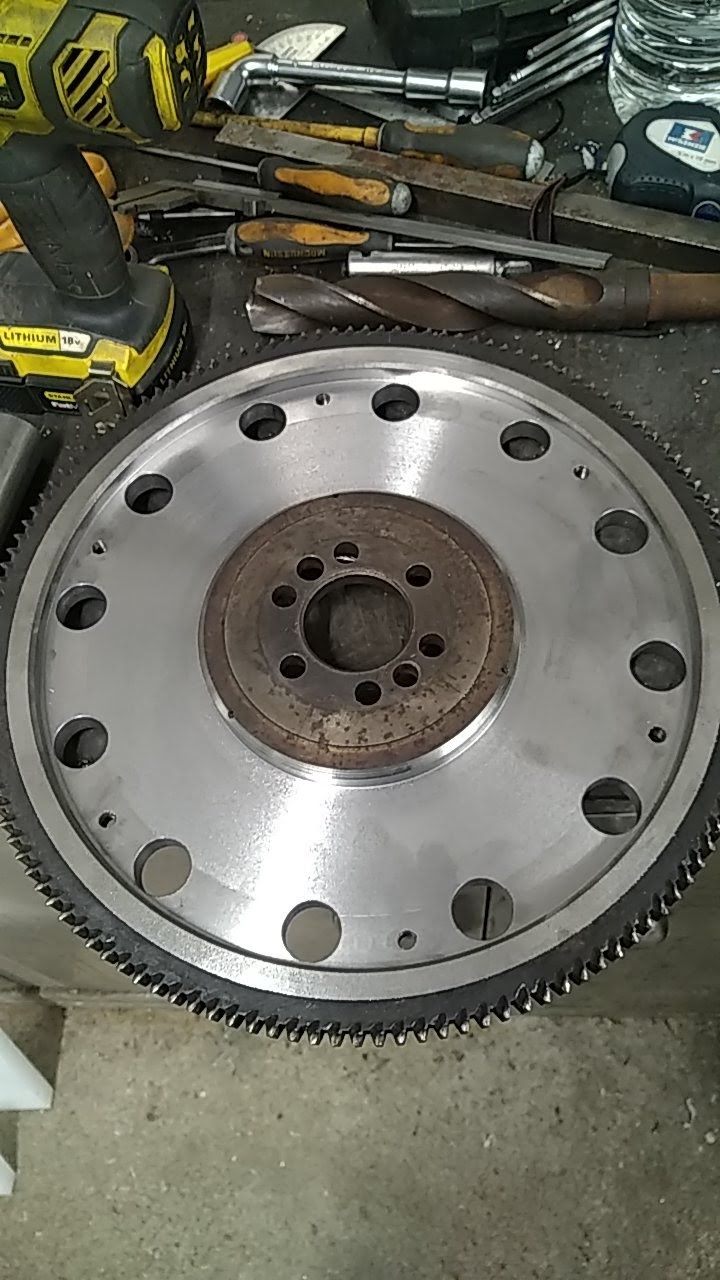 Un volant d'inertie est posé sur une table à côté d'une perceuse.