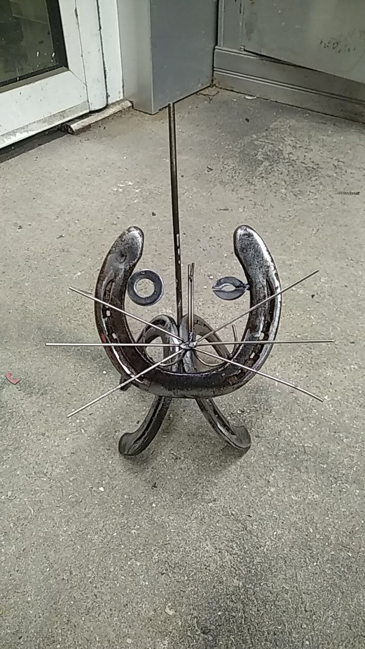 Une horloge faite à partir d'un fer à cheval est posée sur le sol.