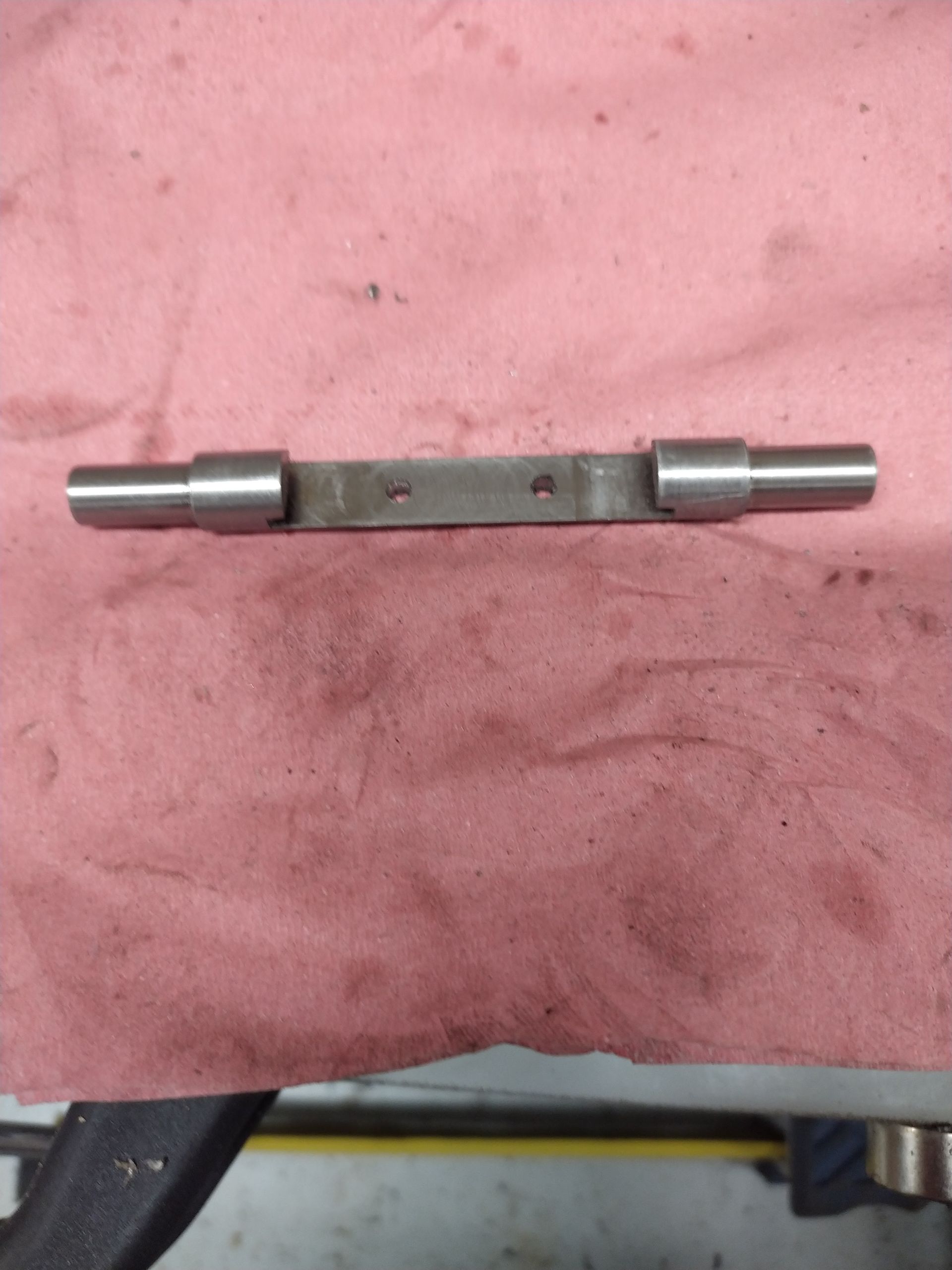 Un morceau de métal est posé sur un tissu rose.