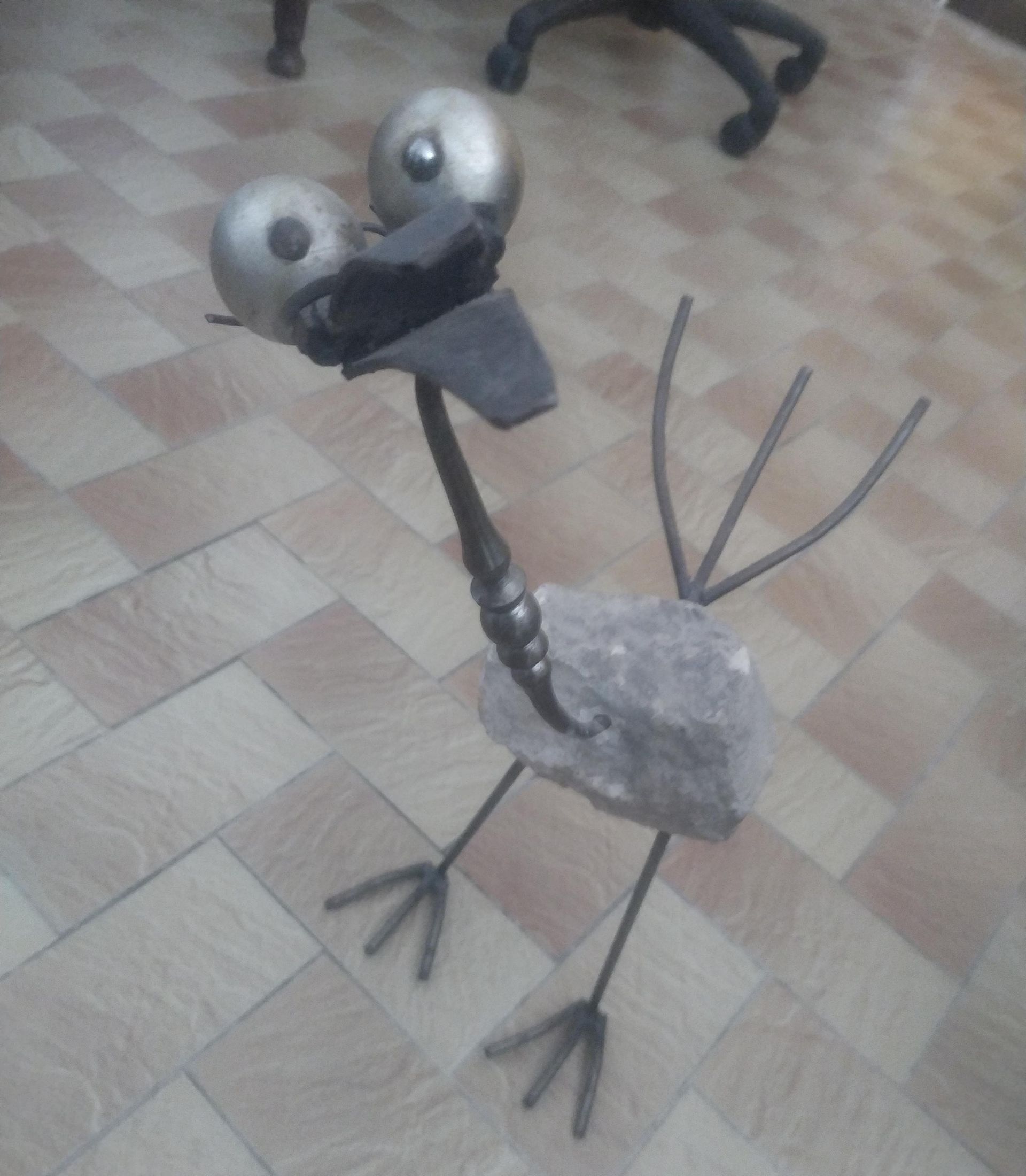 Une statue d'un oiseau debout sur un sol carrelé