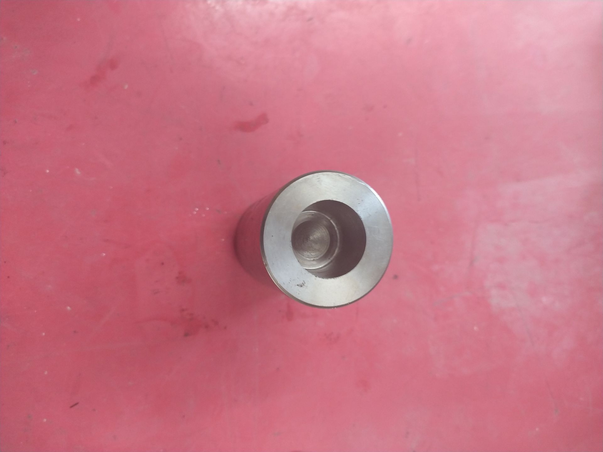 Un petit objet métallique est posé sur une surface rouge.