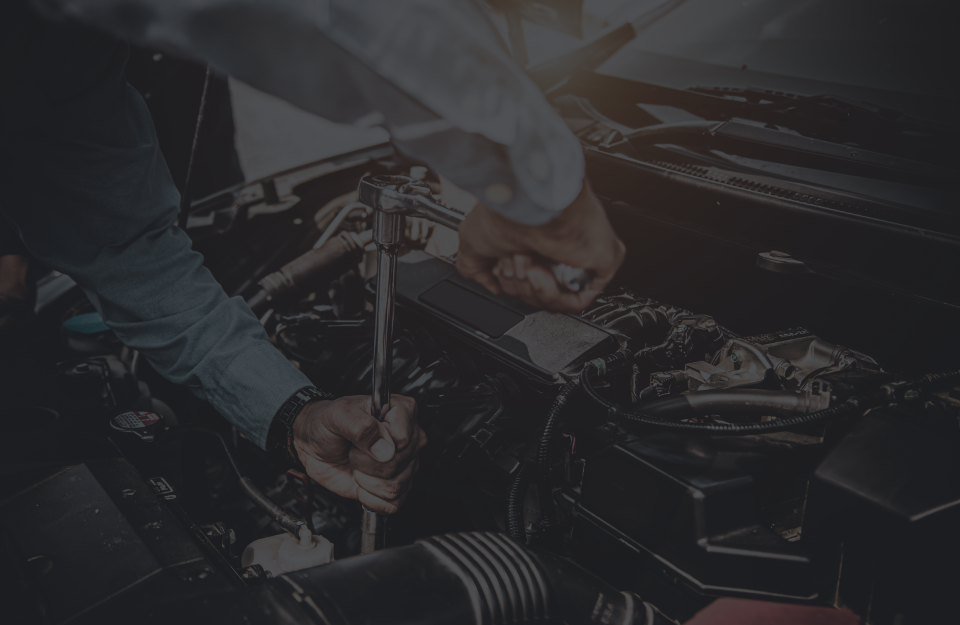 A man is working on the engine of a car with a wrench. | Emerald Automotive