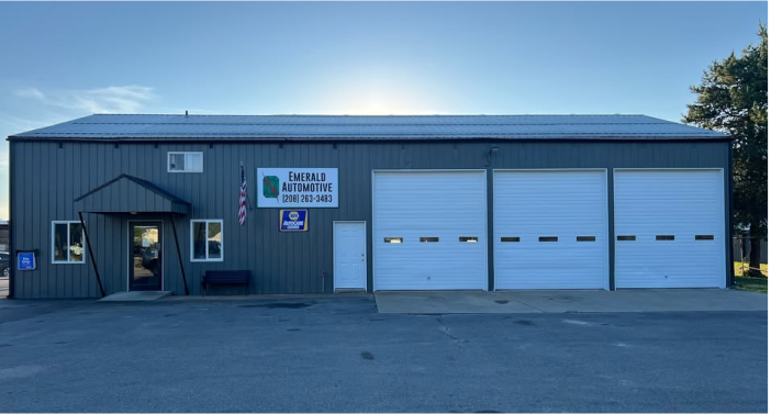 A large gray building with white garage doors and a sign that says ' warehouse ' on it | Emerald Automotive