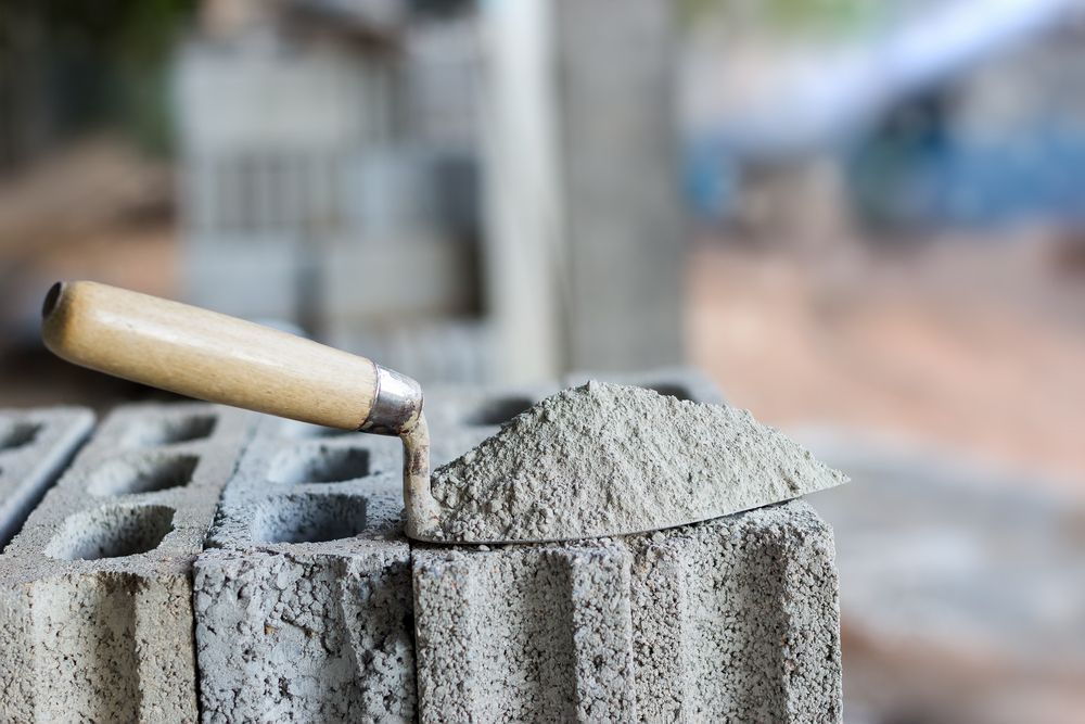 Trowel with A Pile of Gray Mortar Sits on Top of Gray Cinder Blocks — DGW Wholesale Timber & Hardware in Heddon Greta, NSW