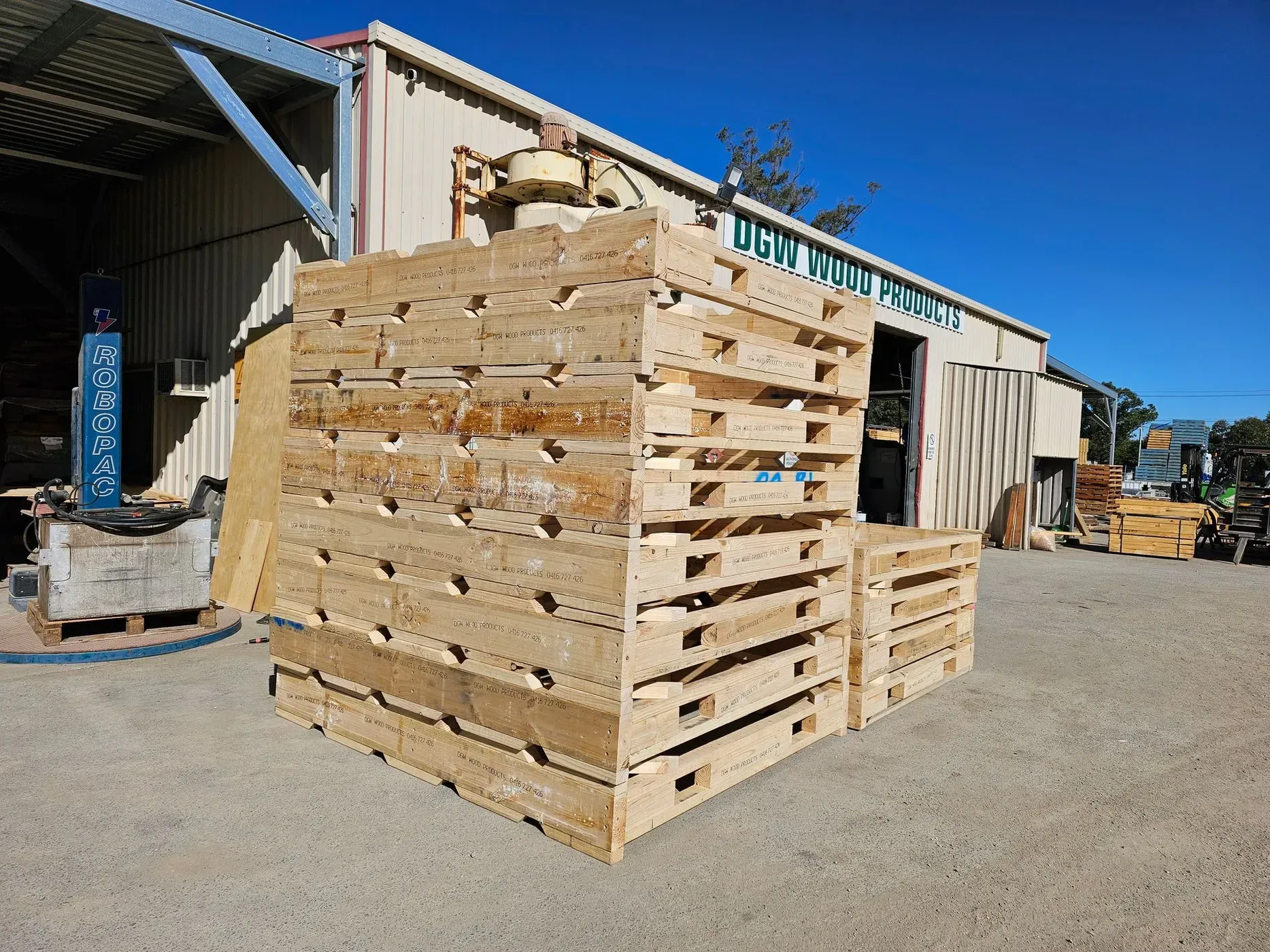 Stacked Wooden Pallets Outside a Building on A Sunny Day — DGW Wholesale Timber & Hardware in Maitland, NSW