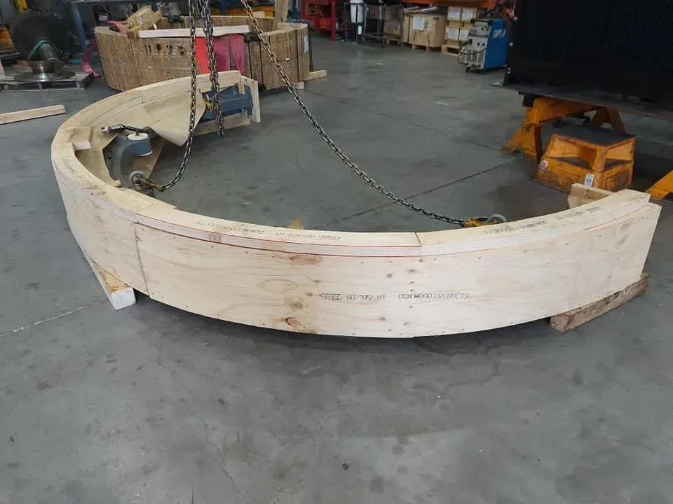 Curved Wooden Structure Being Lifted by A Crane in A Warehouse Setting — DGW Wholesale Timber & Hardware in Singleton, NSW