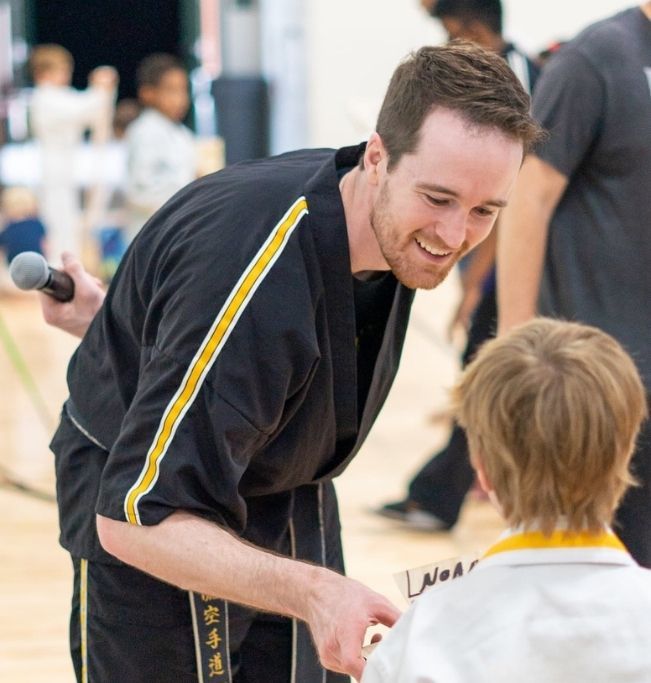 Two people practicing Brazilian Jiu-Jitsu on a mat; one in a black gi, one in a white gi, grappling.