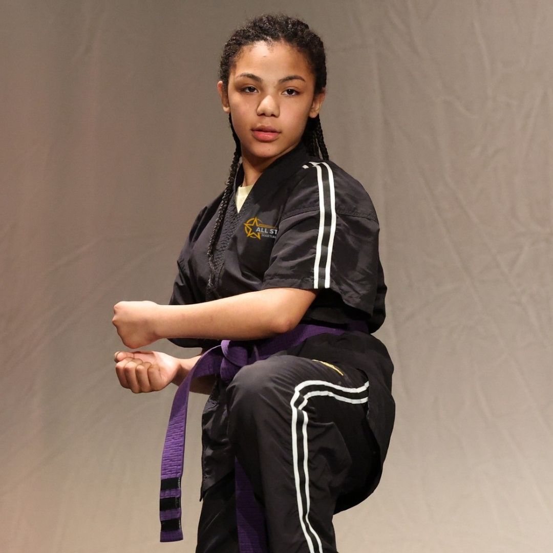 Two boys on a mat practicing Jiu-Jitsu. One boy is on top, giving a thumbs-up.