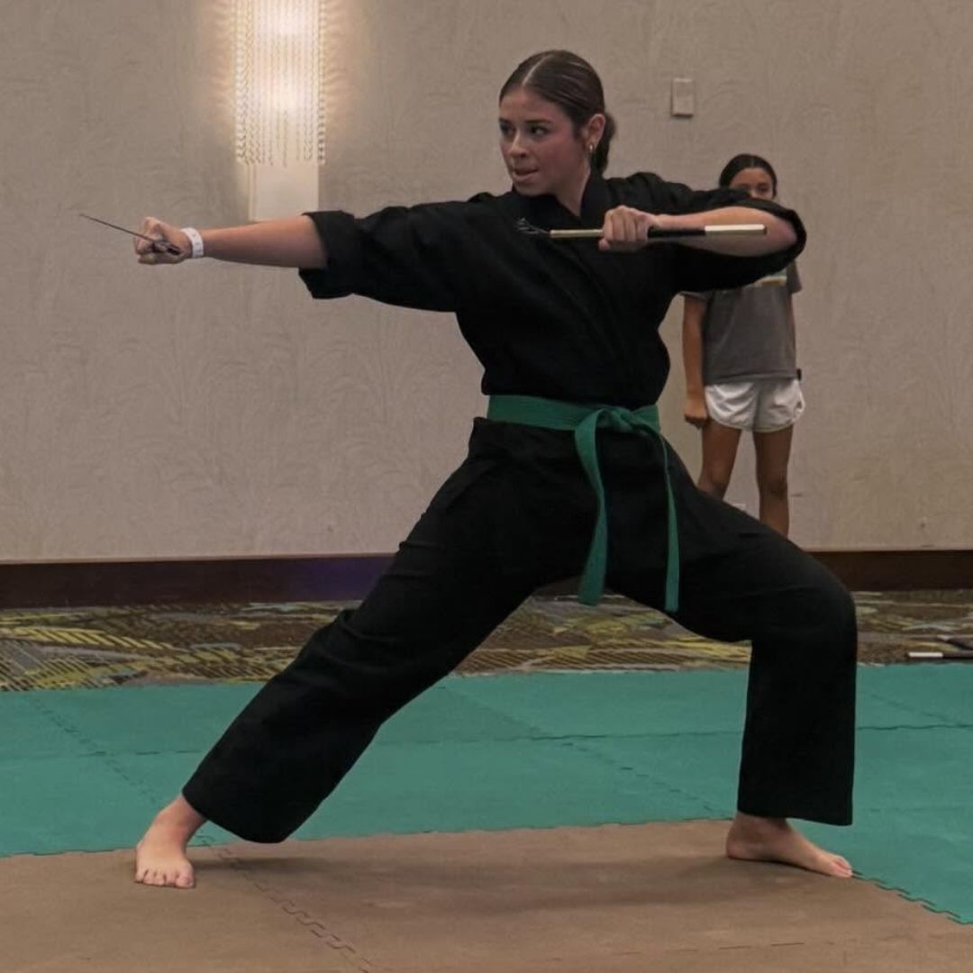 Two children grappling on a mat, one in a headlock.