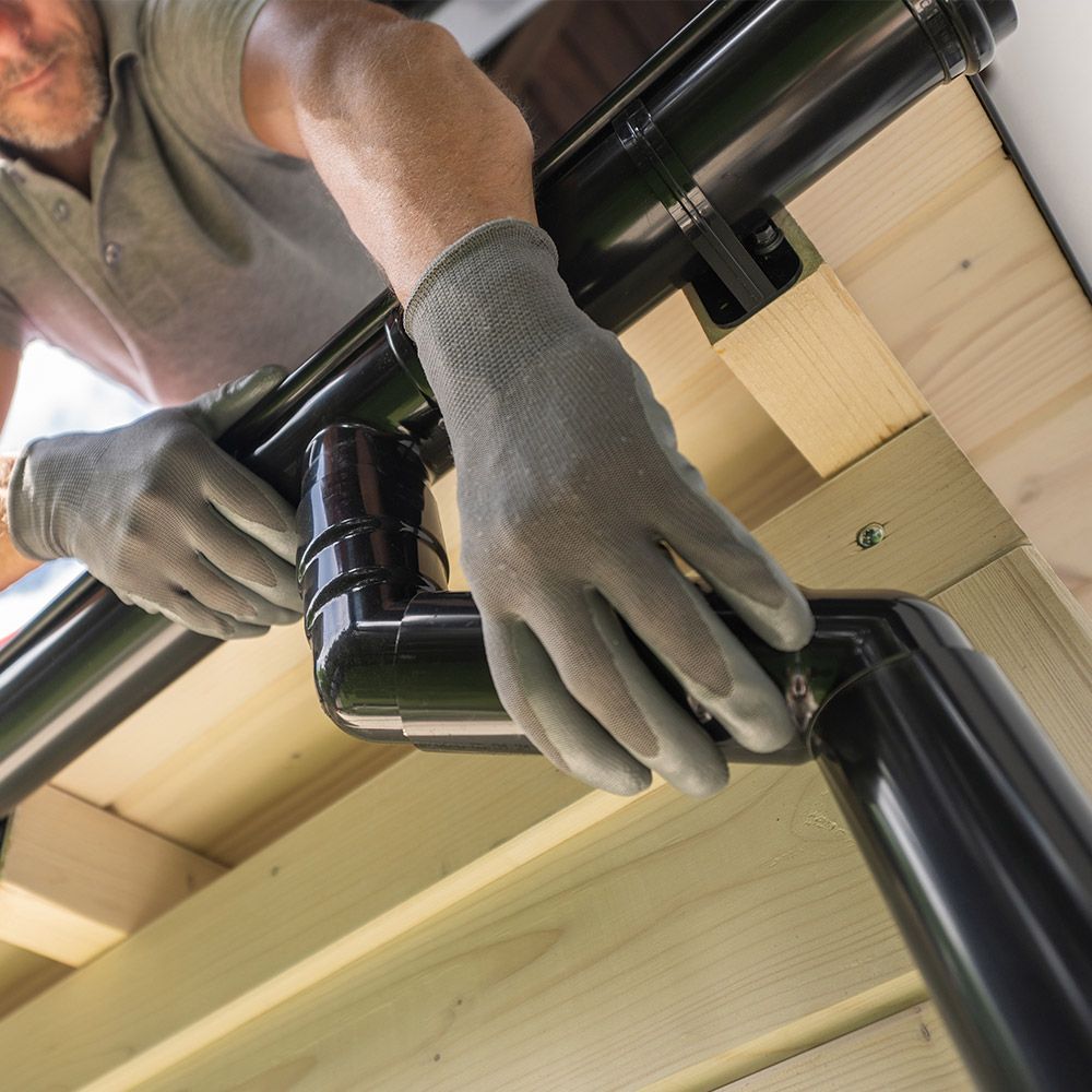 A man wearing gloves is working on a pipe