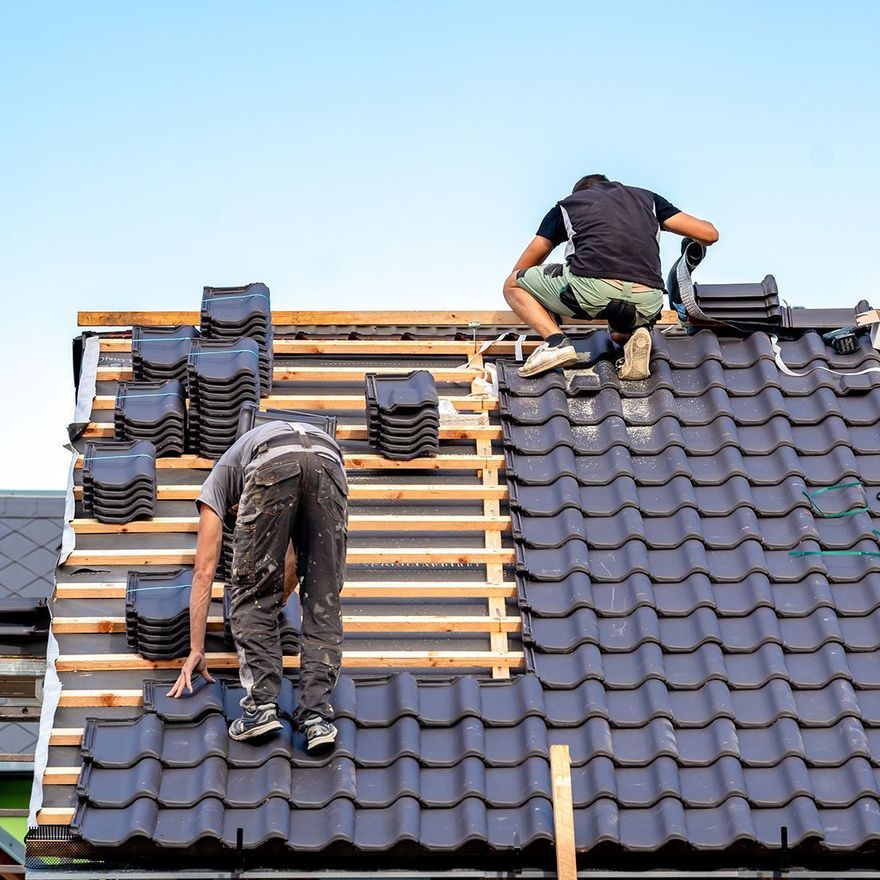 Two men are working on the roof of a house.