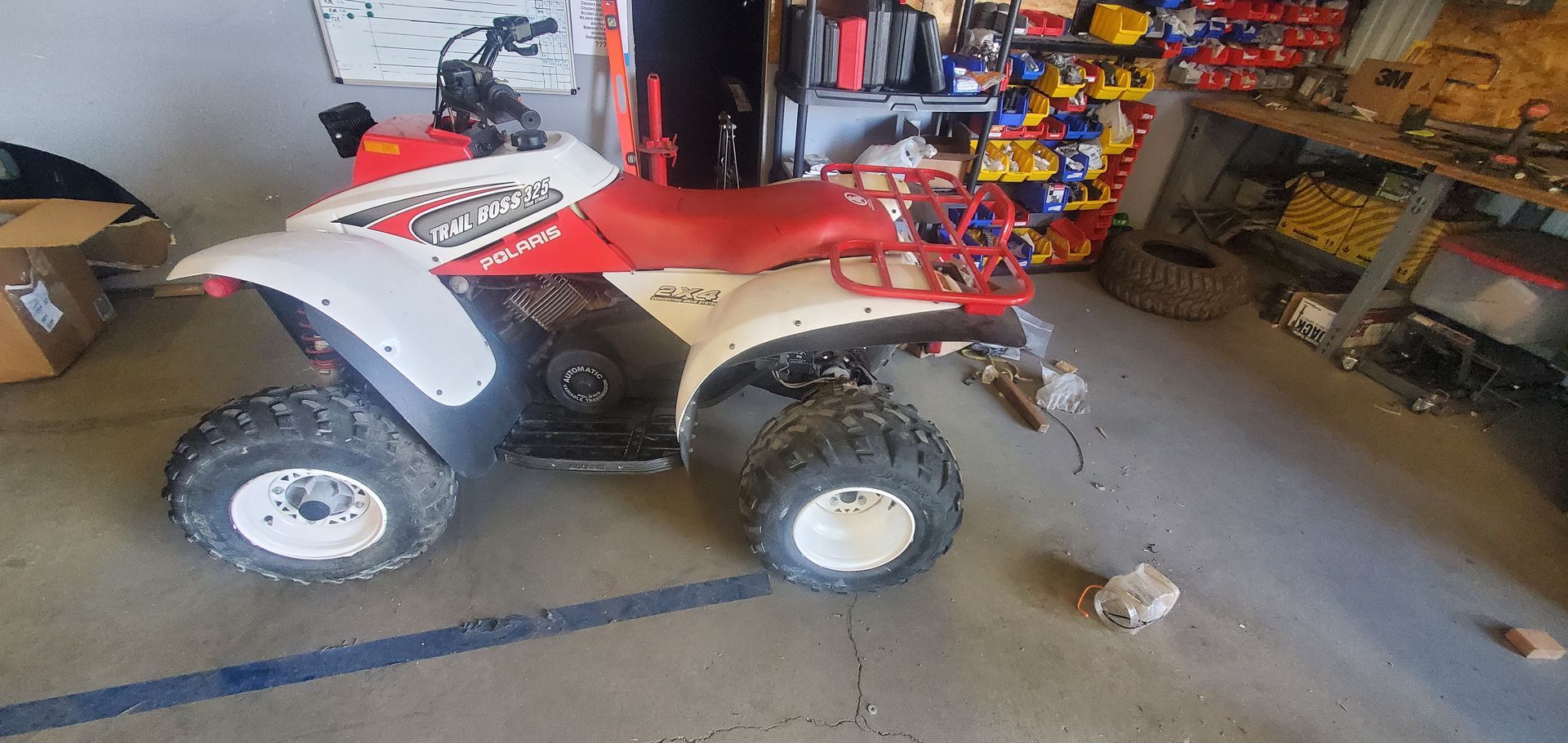 a red and white atv is parked in a garage .