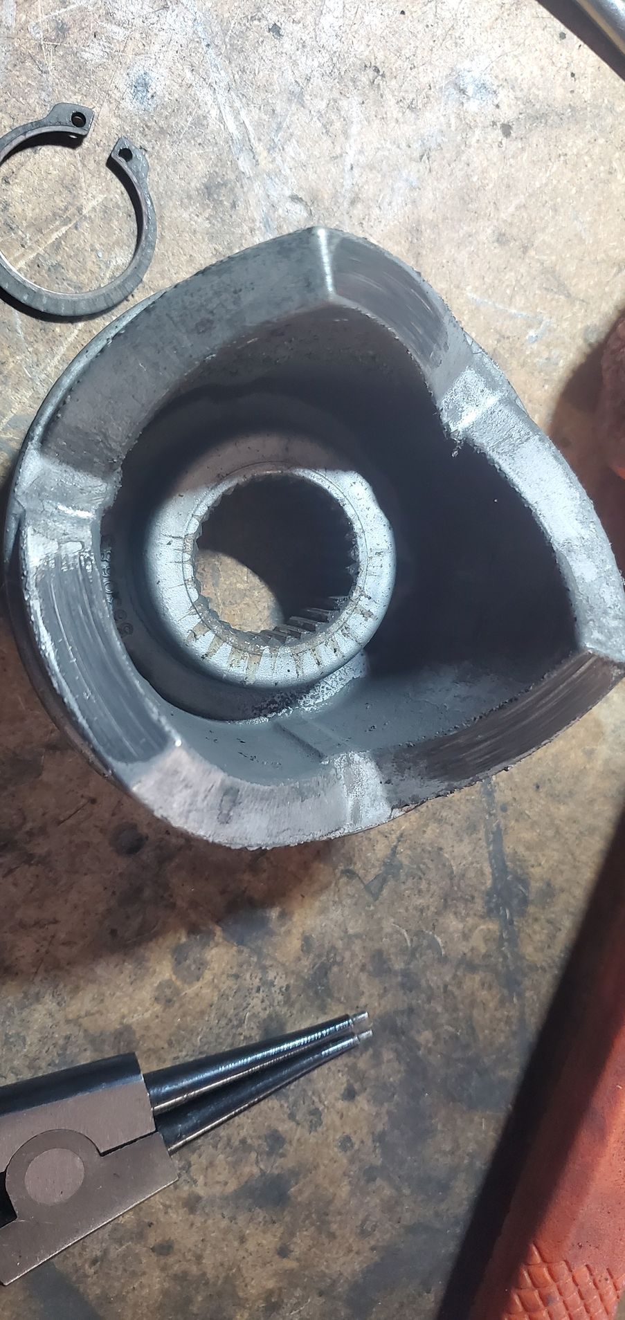 a piece of metal with a hole in it is sitting on a table next to a pair of pliers .