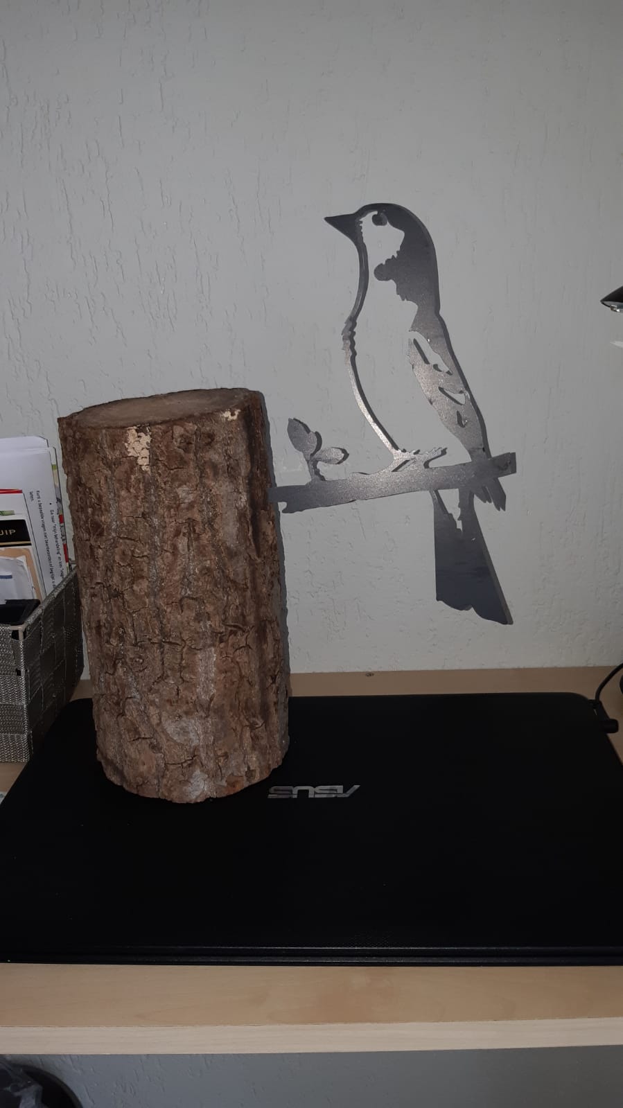 Een vogel zit op een boomstronk op een bureau.