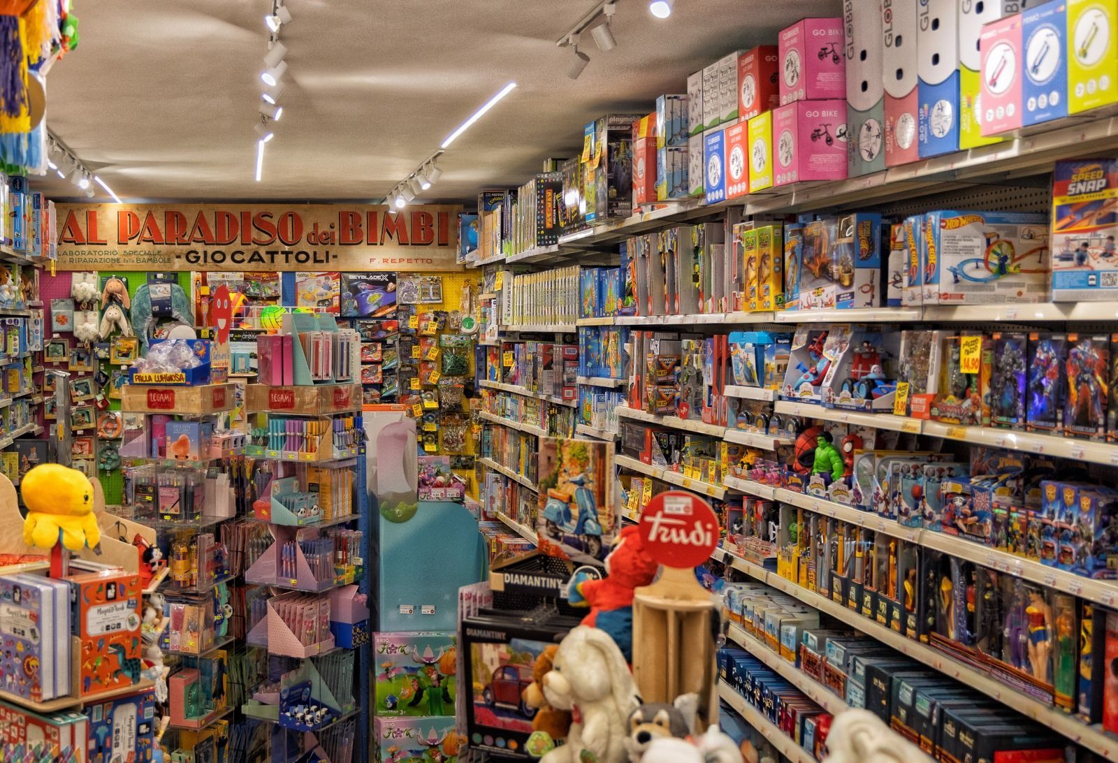 Interno di un negozio di giocattoli con scaffali pieni di giocattoli e un cartello con la scritta 