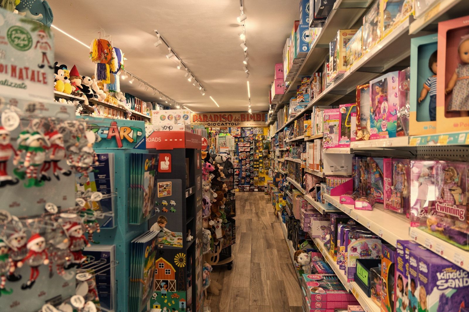 All'interno di un negozio di giocattoli, scaffali pieni di giocattoli si allineano lungo uno stretto corridoio.