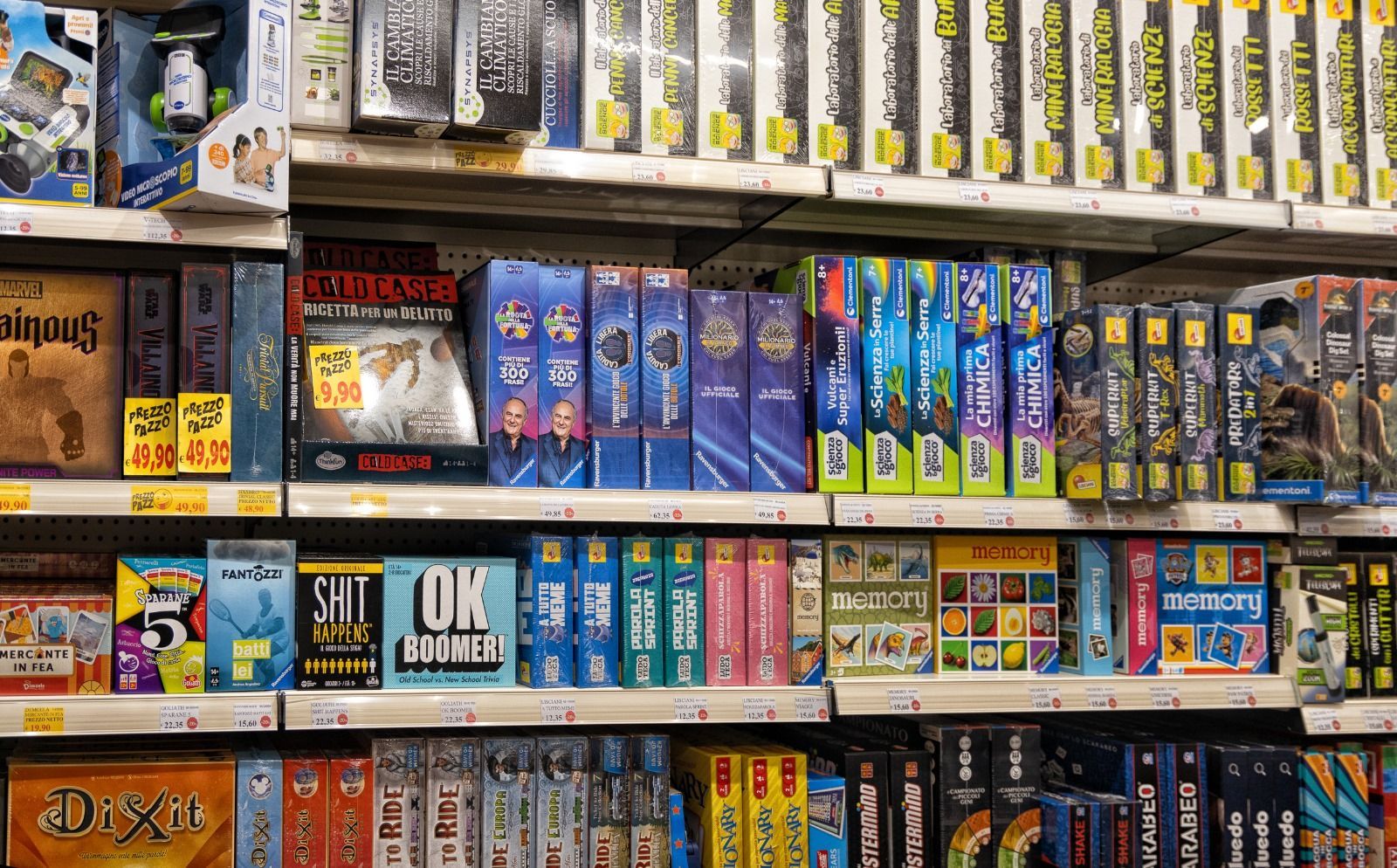 Scaffali pieni di vari giochi da tavolo in un negozio. Le scatole colorate dei giochi sono disposte in modo ordinato.